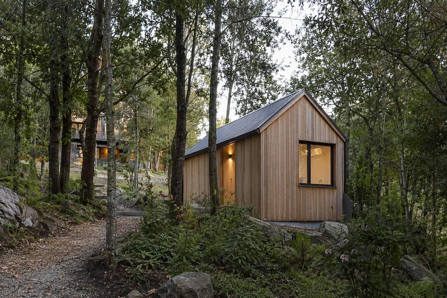 Borde vegetal de Base Arrayán con sendero, unidad compacta y vivienda existente entre los árboles.